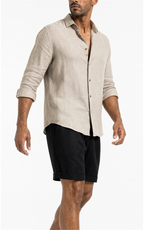 Model in beige linen shirt wearing black pleated shorts, side view