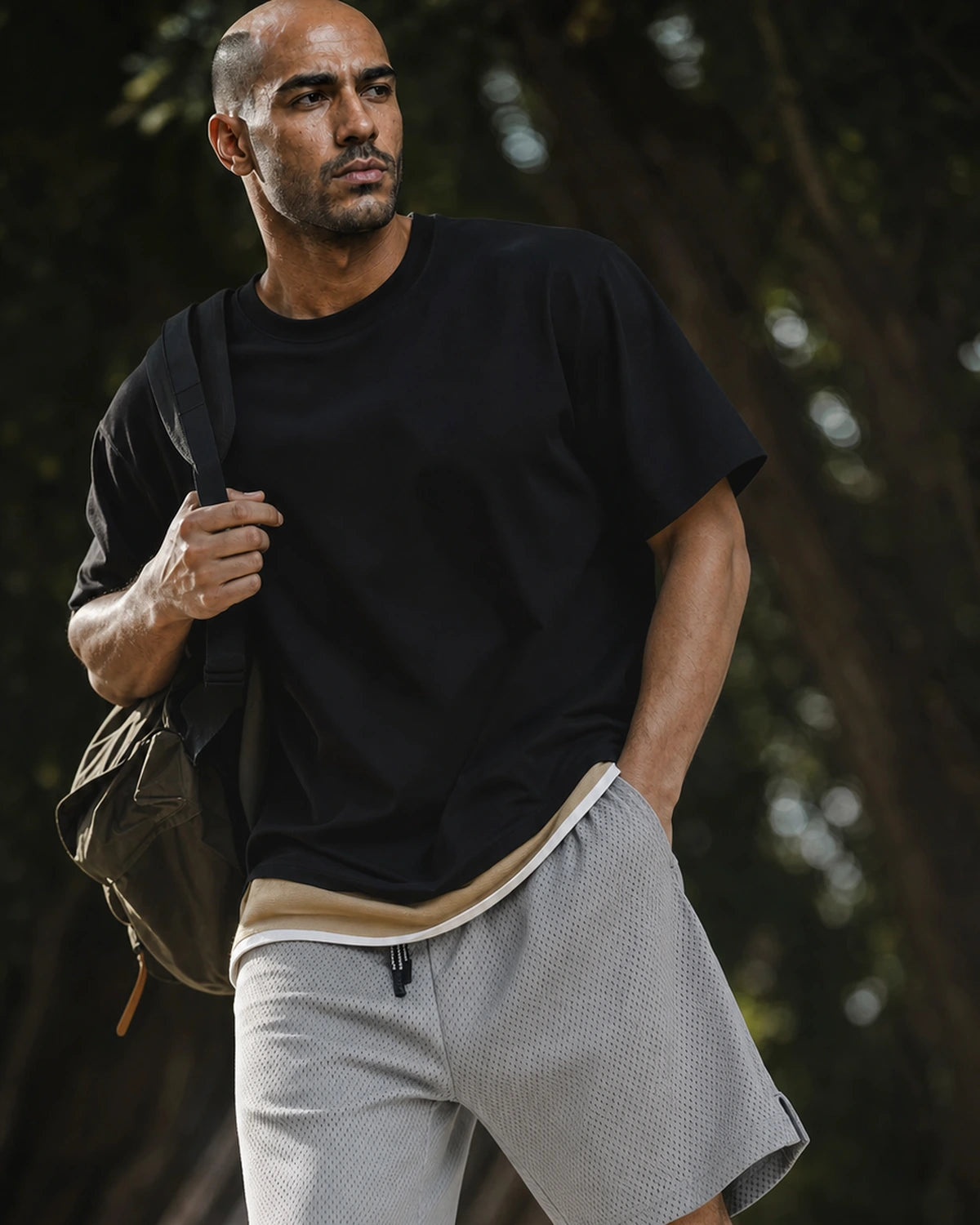 Man with backpack in lead gray mesh shorts and black tee