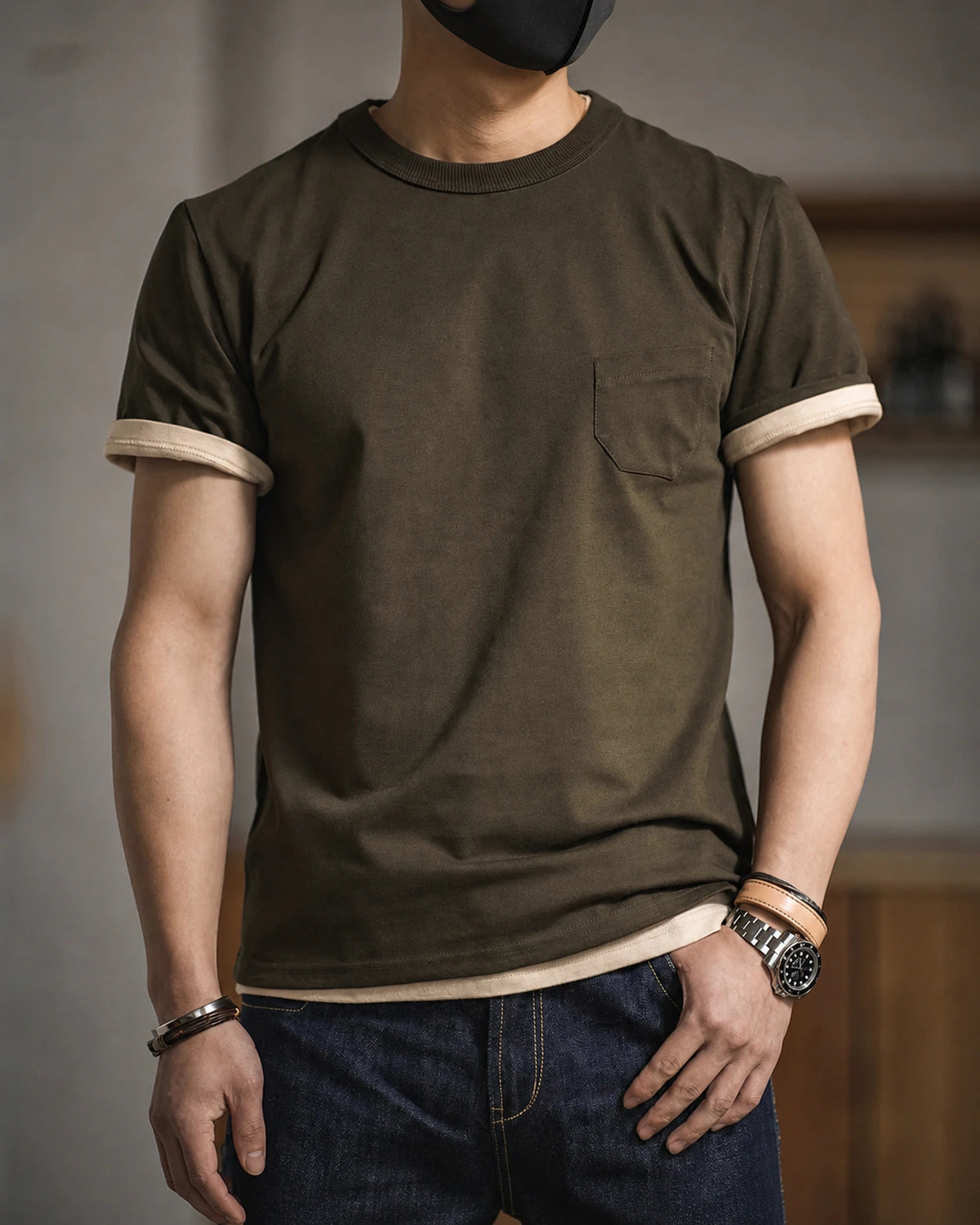 Man wearing the graphite green pocket tee with dark jeans, sleeves rolled