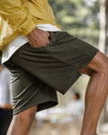 Dense mesh texture of army green shorts with yellow anorak — close-up