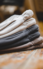 Folded stack of cream, charcoal and taupe knit shorts on wooden table