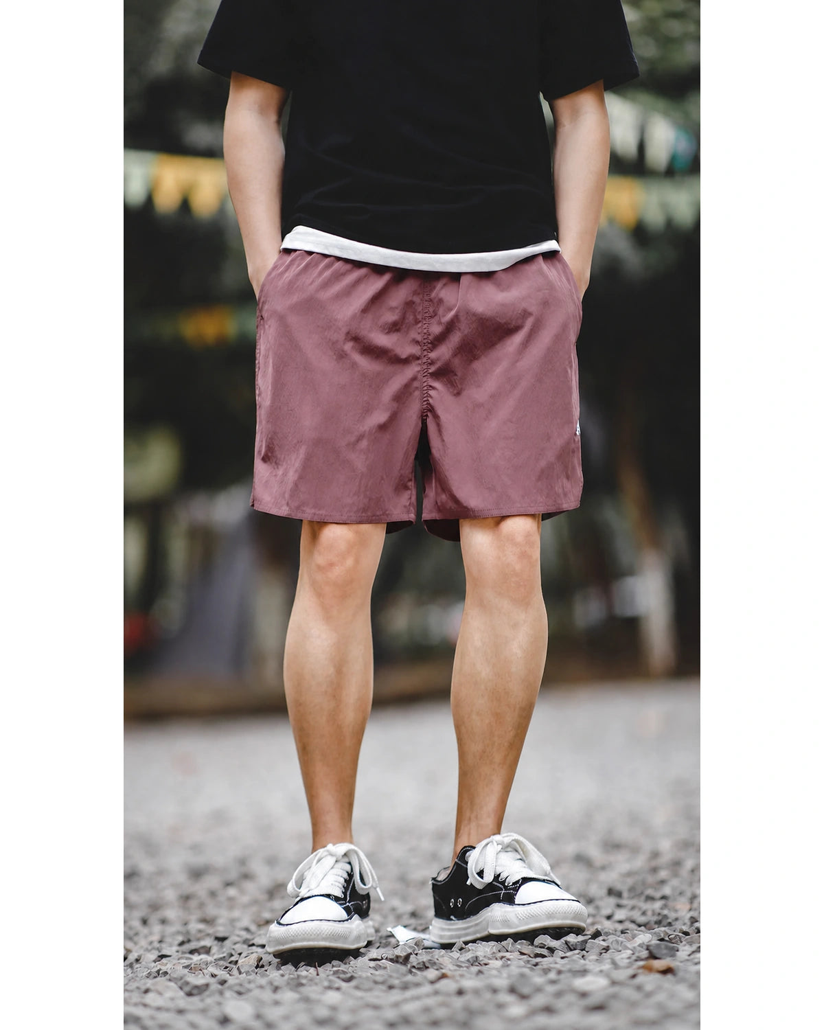 Full front: washed burgundy PT-style shorts, outdoor gravel