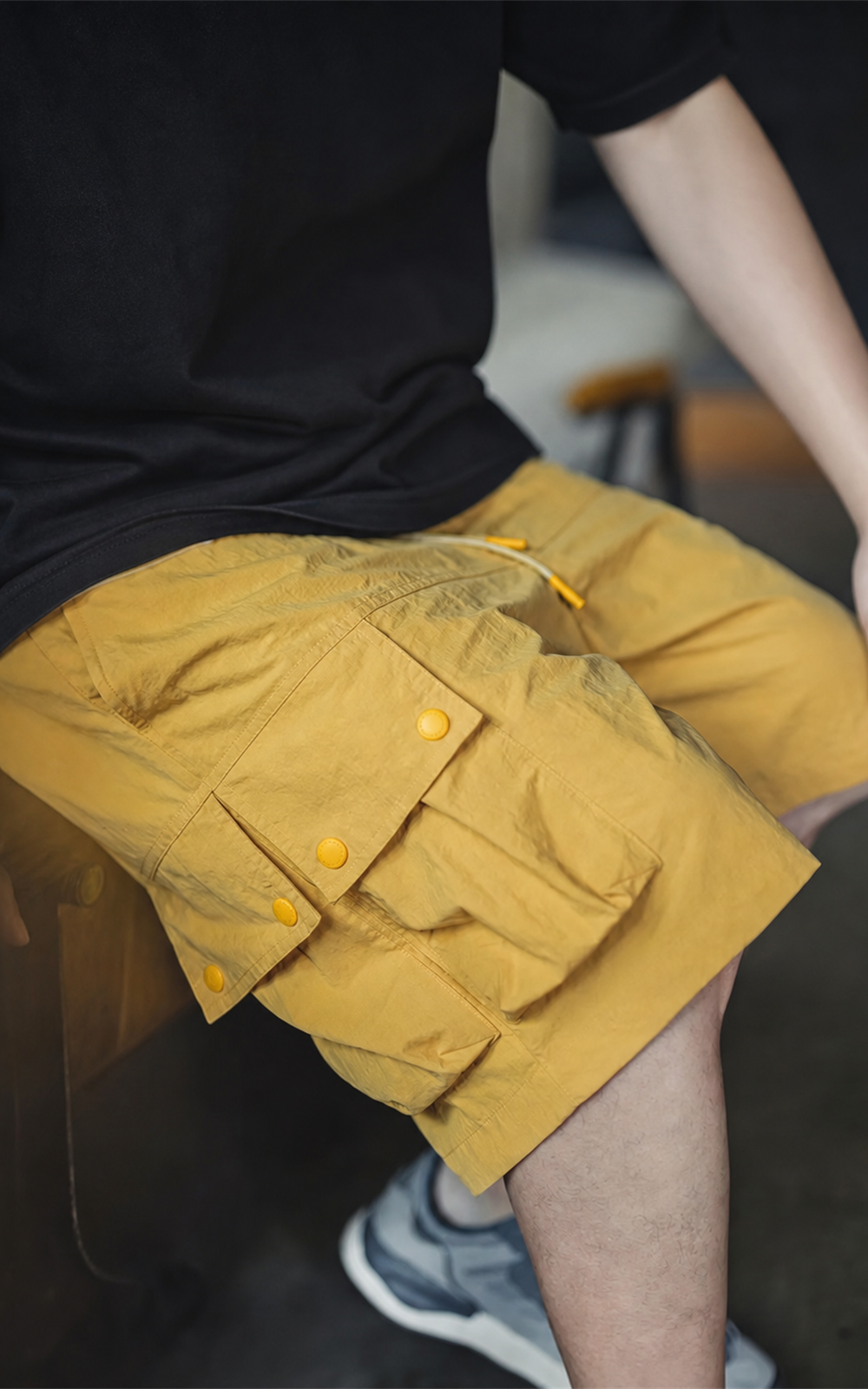 Yellow cargo shorts worn sitting — snap-flap utility pockets