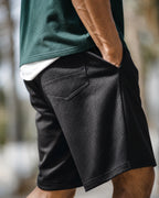 Side view: black mesh shorts, hand in pocket