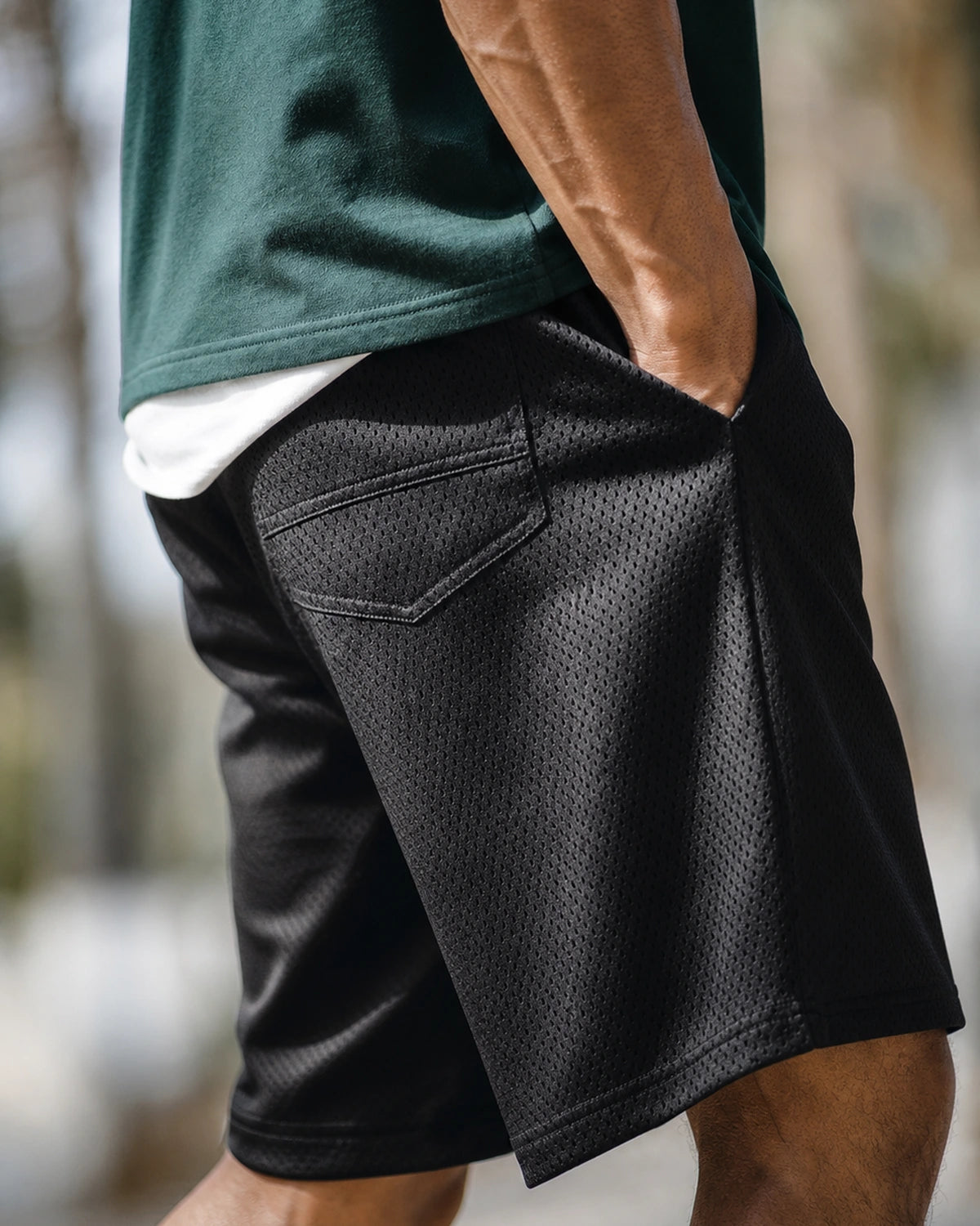 Side view: black mesh shorts, hand in pocket