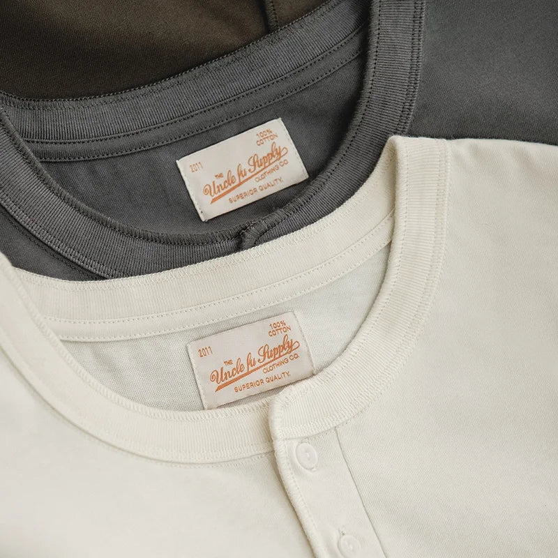 Stacked cold gray and almond white henleys showing placket and label detail