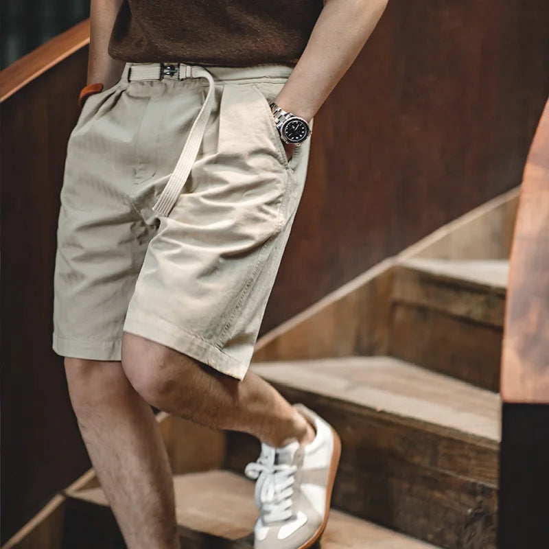 Apricot shorts worn with brown knit T-shirt, hand in slant pocket
