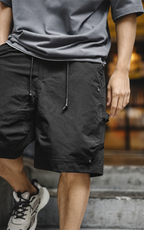 Black carpenter shorts with drawcords — model on steps