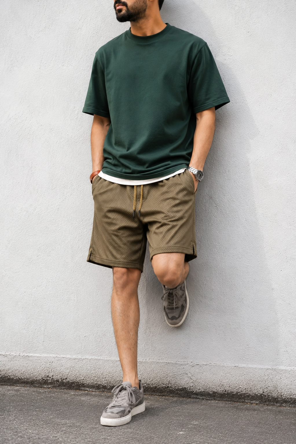 Army green mesh shorts with dark green tee — wall lean