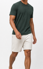 Model in green tee walking in cream knit shorts, studio view