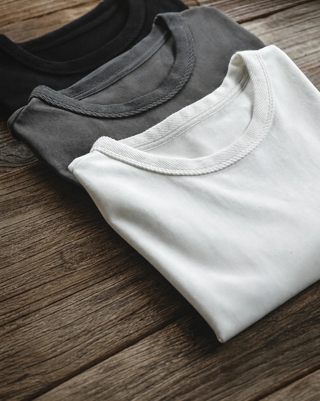 Stacked grey, white and black heavyweight tees showing collar detail