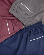 Flat-lay: burgundy, grey, and navy training shorts with white-piped pockets