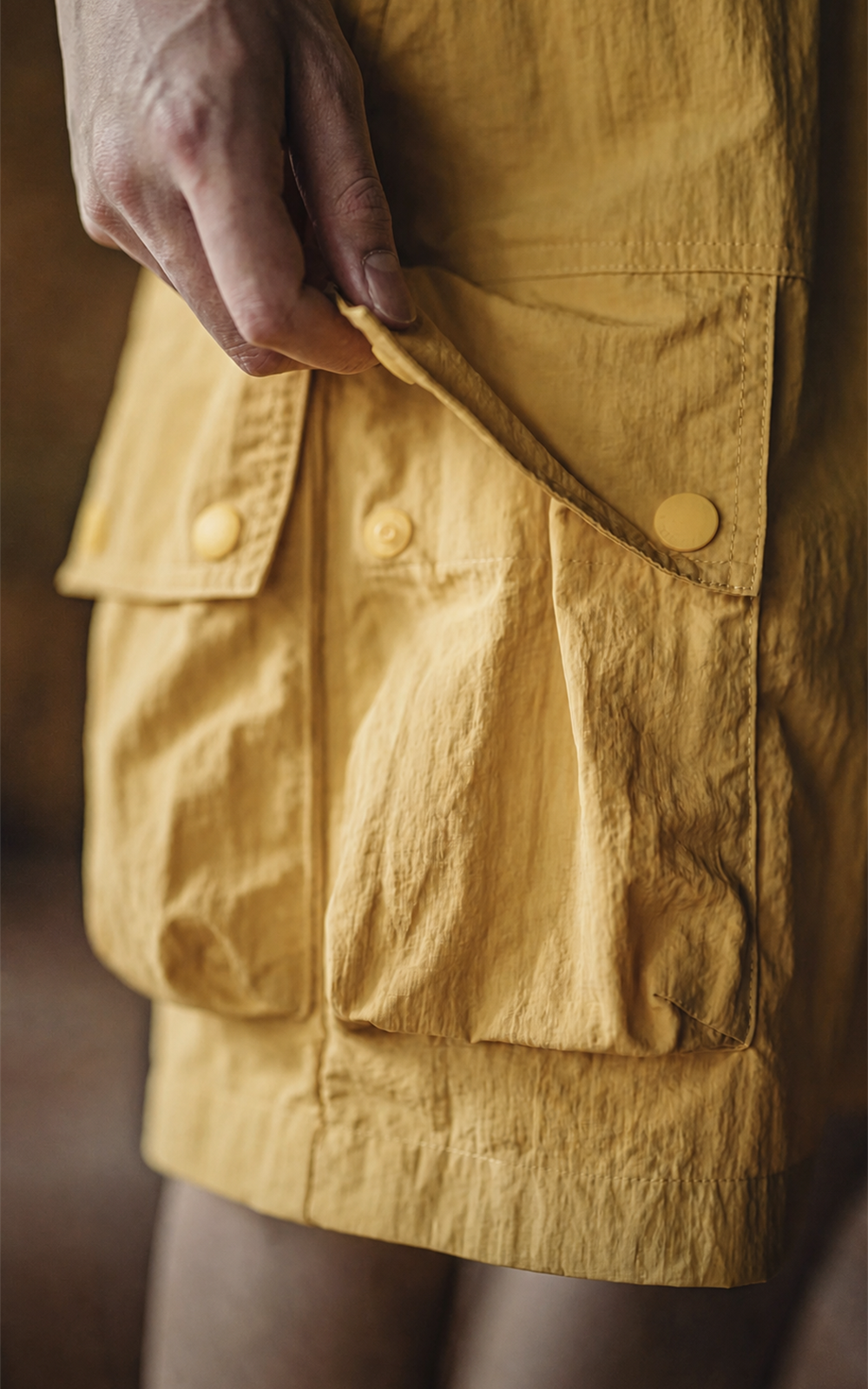 Close-up of stacked snap pockets on yellow cargo shorts