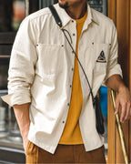 Close view of the overshirt worn open with crossbody bag and mustard tee