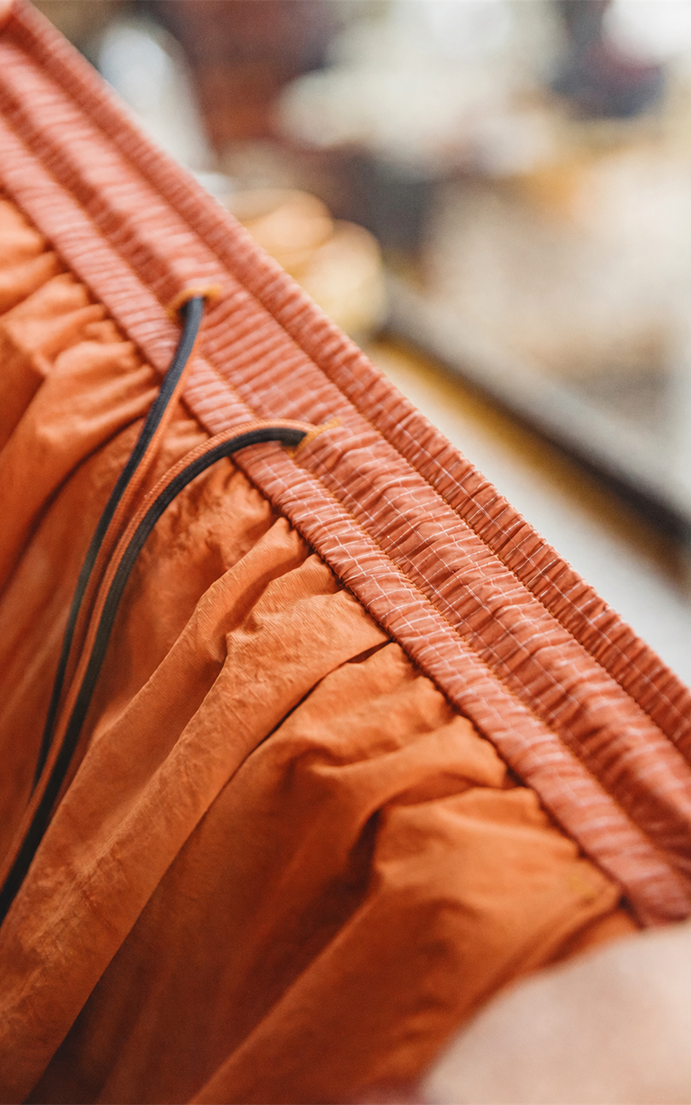 Elastic drawstring waistband of orange nylon shorts — detail