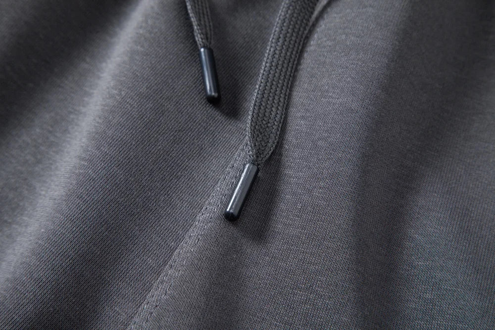 Detail of braided drawcords with black tips on dark gray shorts