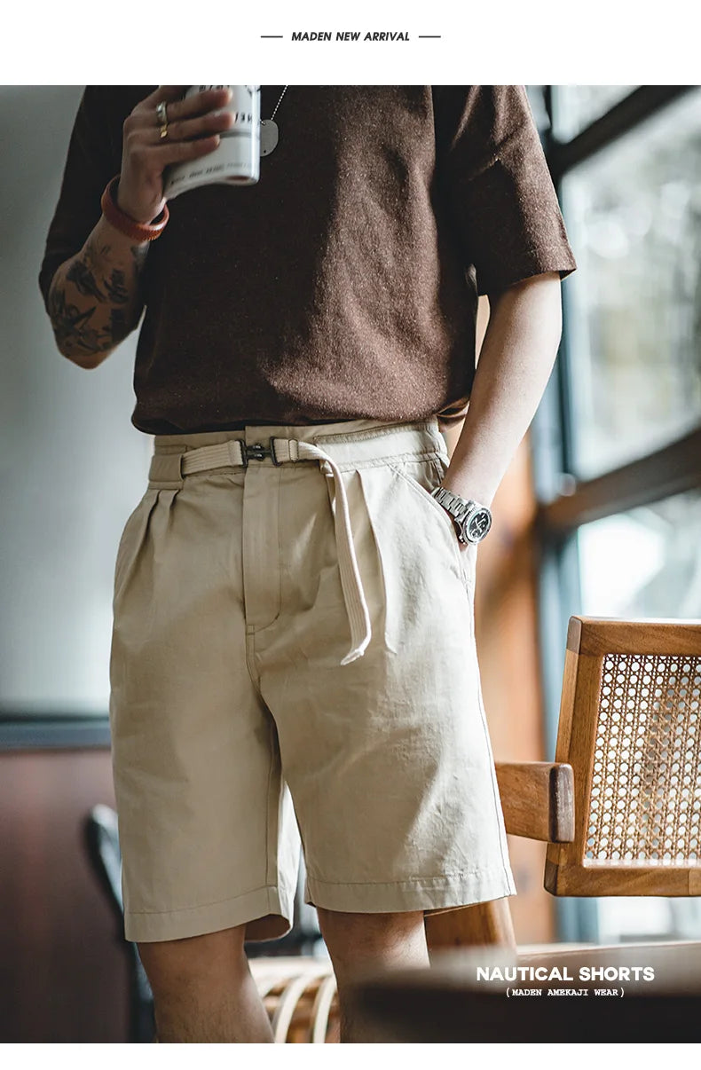 Man standing by window wearing apricot belted shorts with brown T-shirt