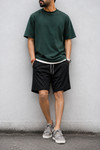 Black mesh shorts with dark green tee and grey sneakers — full look