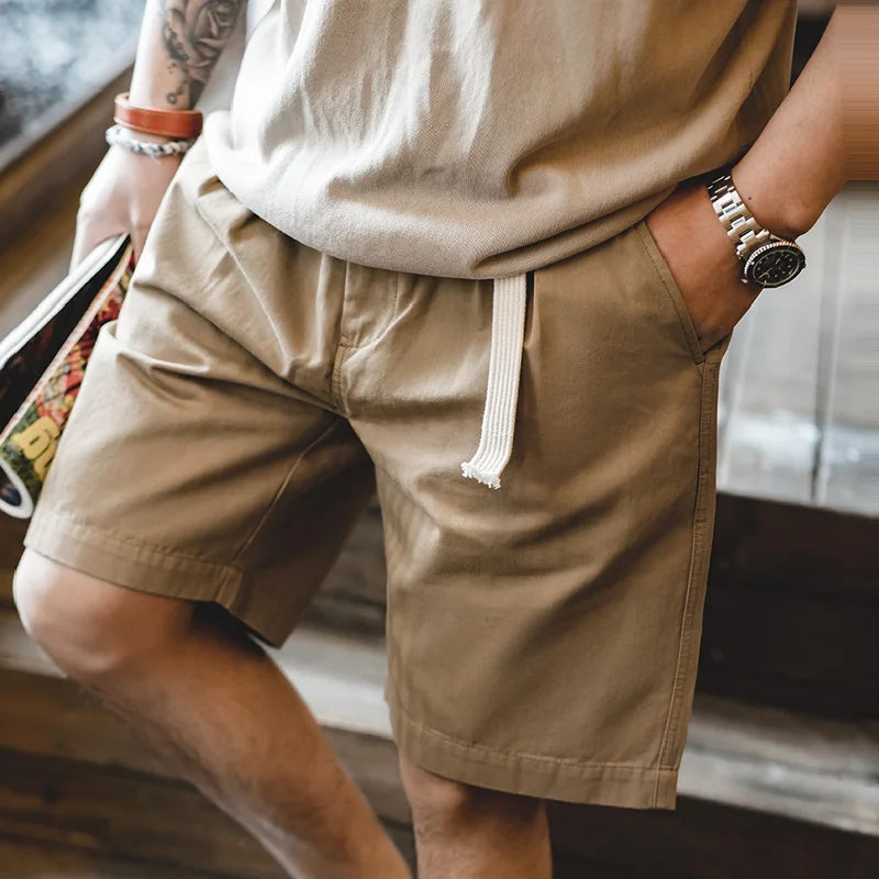Close-up of khaki shorts front pleats and hanging white webbing belt