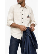 Man in the off-white overshirt with blue jeans, holding a denim jacket