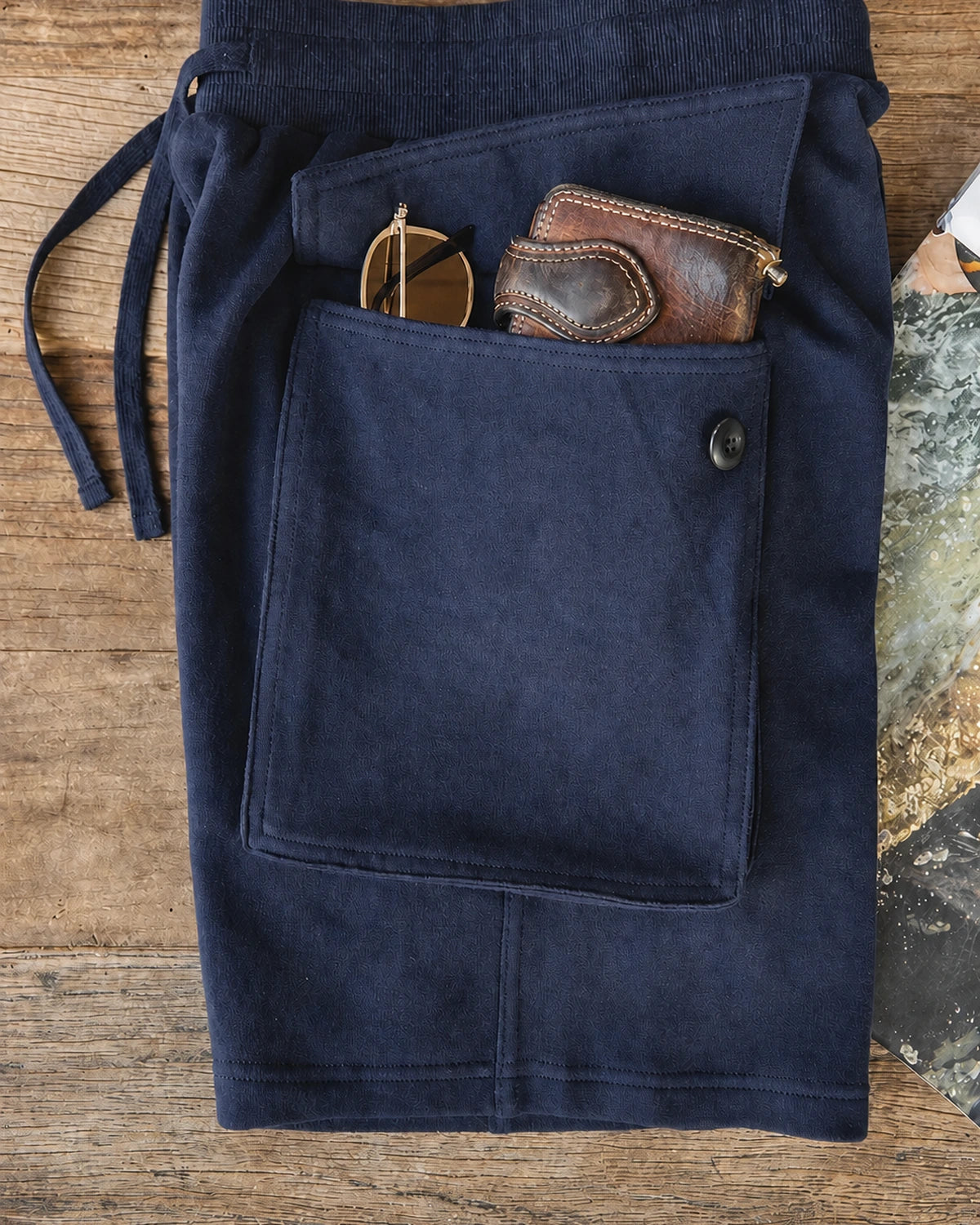 Flat lay: wallet and sunglasses inside cargo pocket of navy shorts
