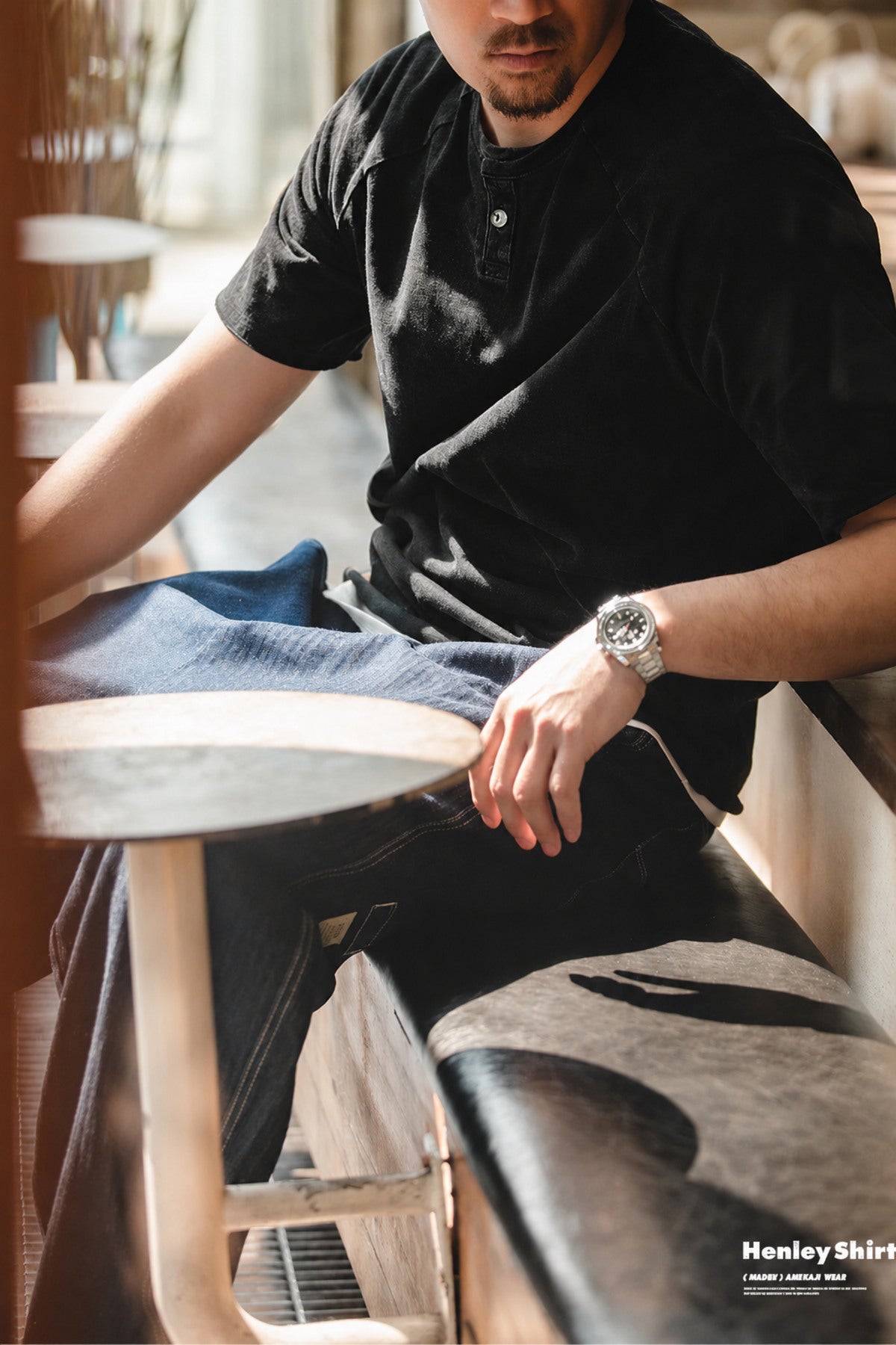 Seated man wearing the washed black henley at a cafe