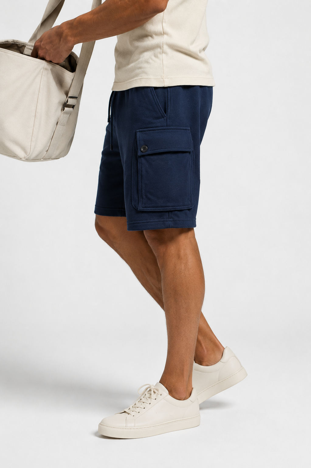 Side view: navy cargo sweat shorts with cream tee and tote