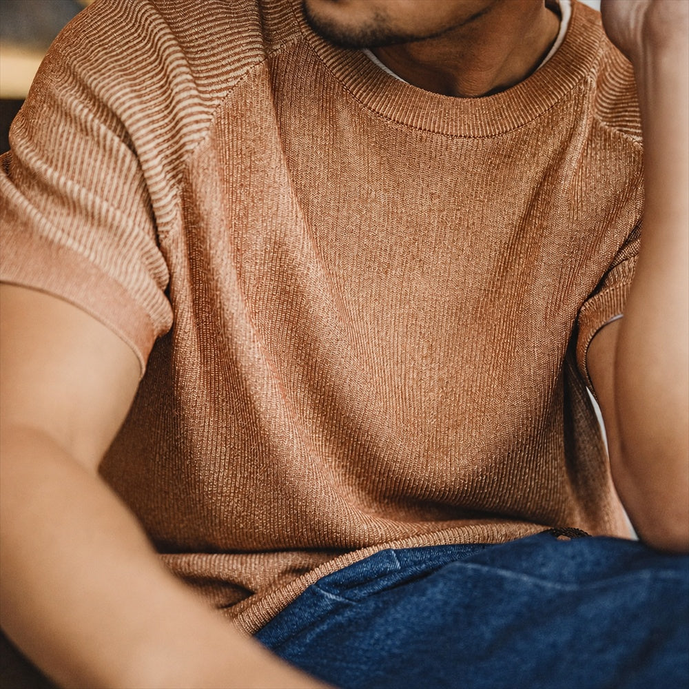 Seated close view of the terracotta knitted tee with denim