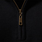 Close-up of the antique-gold half zip and ribbed mock collar on the black knit pullover