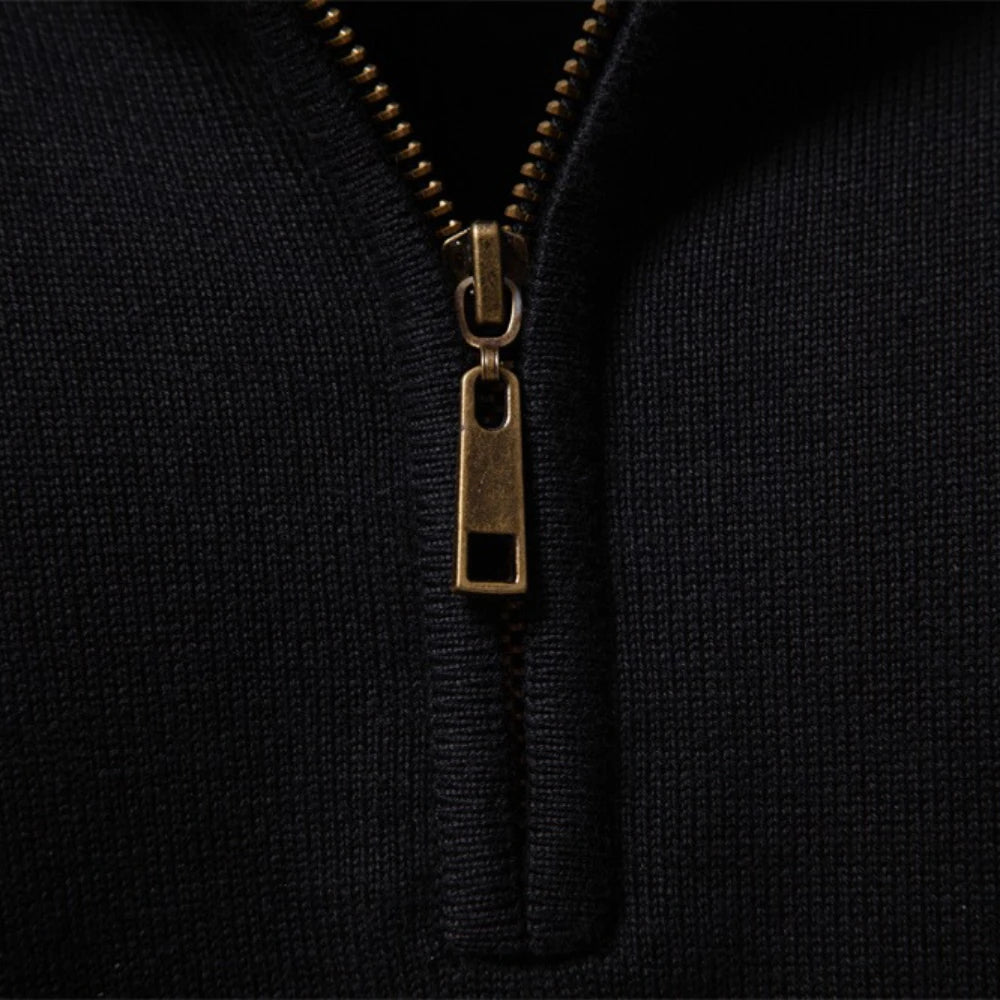 Close-up of the antique-gold half zip and ribbed mock collar on the black knit pullover