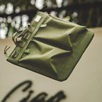 Close view of the Military Green bag's front pockets and strap tab closures