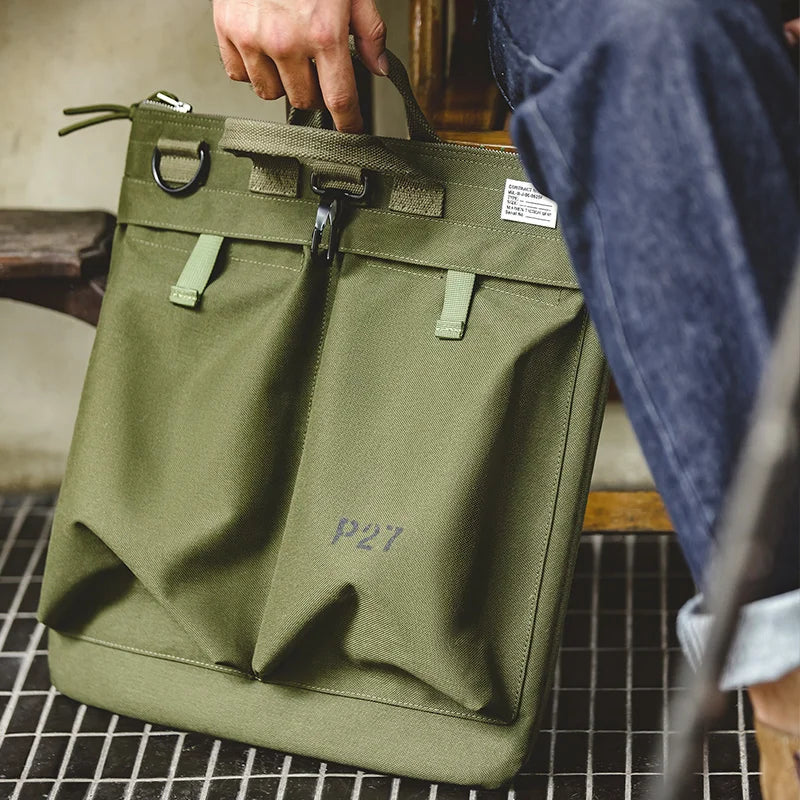 Military Green bag loaded with a laptop, magazine, sunglasses and gloves in the front pockets