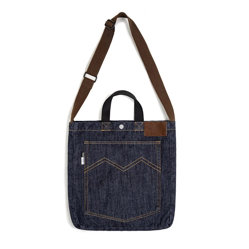 Navy denim tote bag on white showing the strap slider adjuster, top handles and leather corner patch