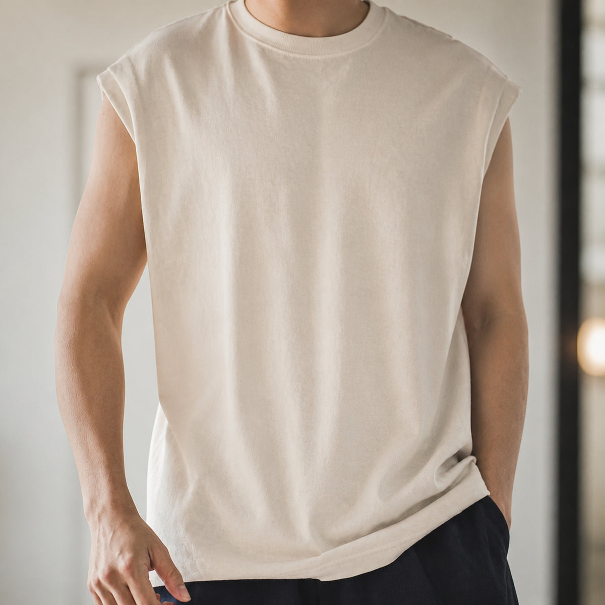 Man wearing the beige knit shoulder vest, front view