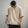 Man wearing the beige oversized boxy tee with dark shorts