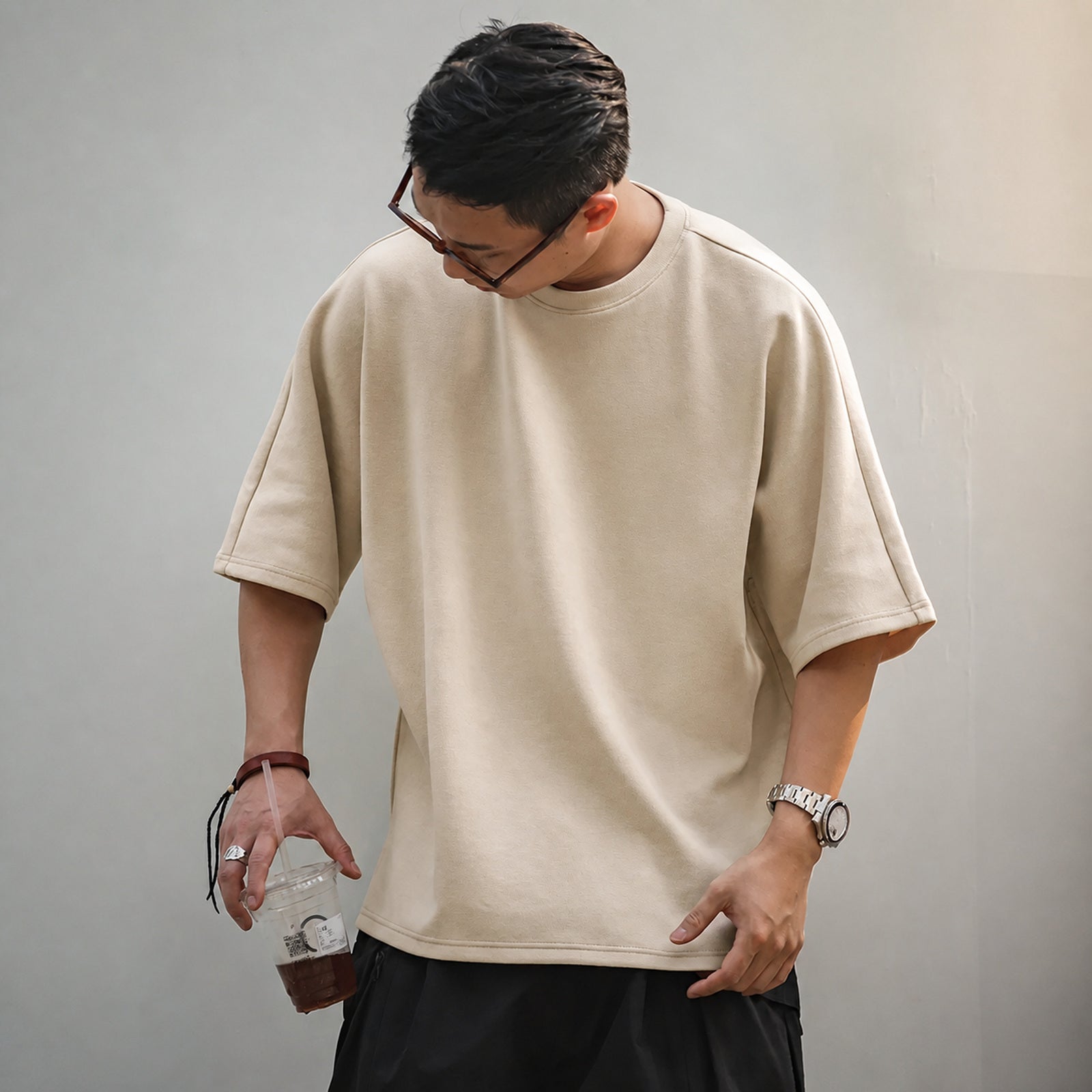 Man wearing the beige oversized boxy tee with dark shorts