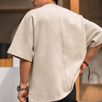 Back view of the beige oversized tee showing the center-back seam
