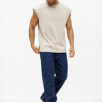 Man wearing the beige knit shoulder vest with navy trousers, full view
