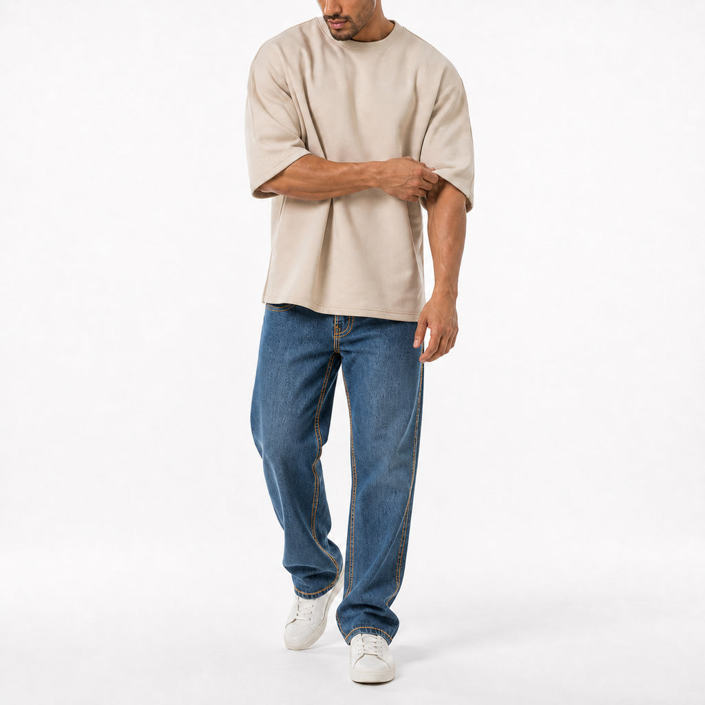 Man wearing the beige oversized boxy tee with blue jeans, full view