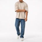 Man wearing the beige oversized boxy tee with blue jeans, full view