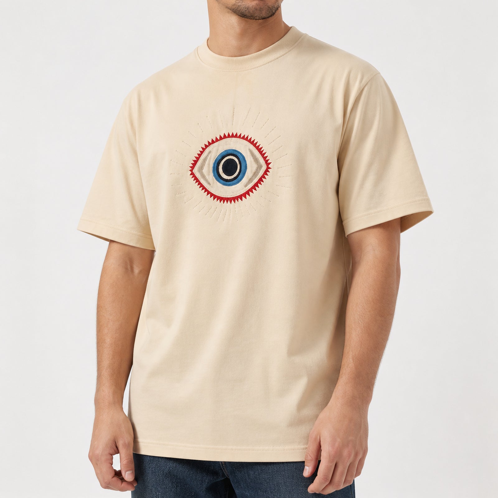 Man in the beige guardian eye embroidered t-shirt, front view