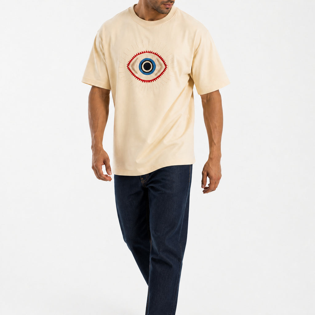 Man wearing the beige guardian eye tee with dark jeans, full view