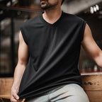 Man wearing the black ribbed v-neck tank with grey trousers