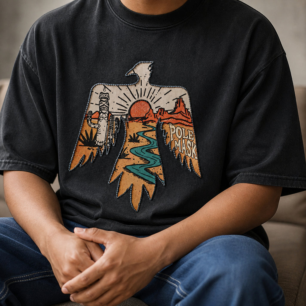Seated man wearing the washed black thunderbird tee with blue jeans