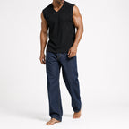 Man in the black ribbed v-neck tank with dark jeans, full view