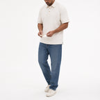 Man wearing the creamy white retro polo with blue jeans, full view