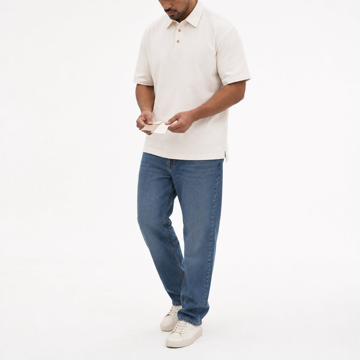 Man wearing the creamy white retro polo with blue jeans, full view