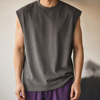 Man in the dark grey boxy sleeveless knit vest, relaxed pose