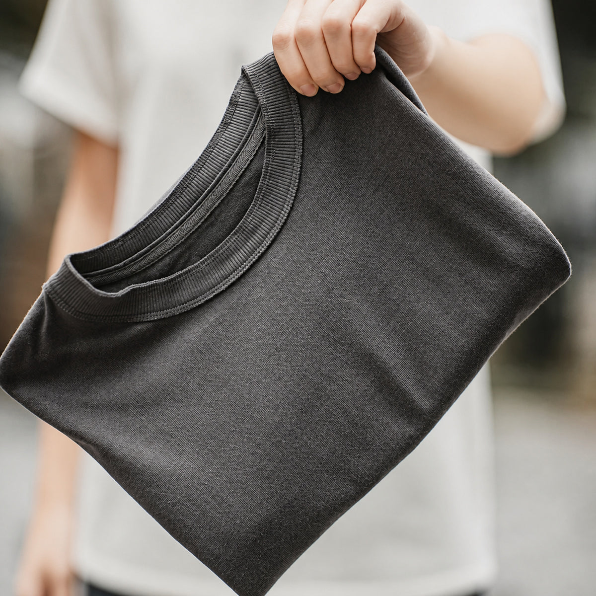 Folded dark grey knit shoulder vest held in hand