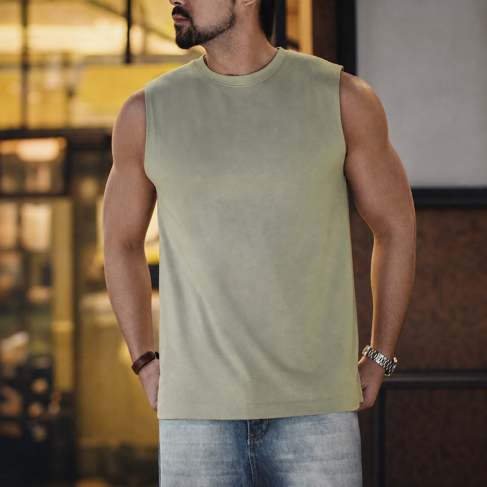 Man wearing the sage green heavyweight tank with light jeans
